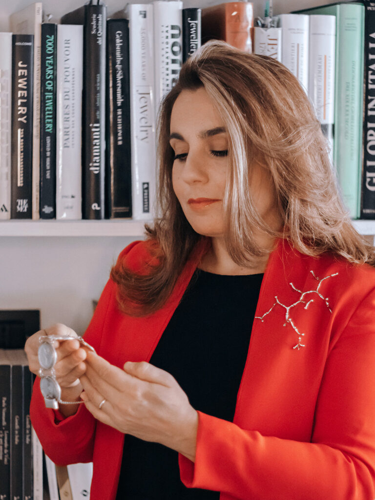 Bianca Cappello examining a silver and moonstone chain in front of her jewellery reference library, photography by Sogand Nobahar