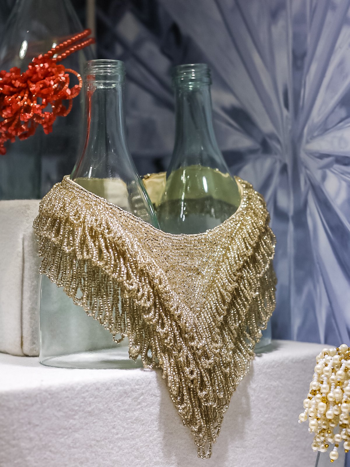Beaded collar draped over recovered bottles in a museum vitrine, display design by Sogand Nobahar