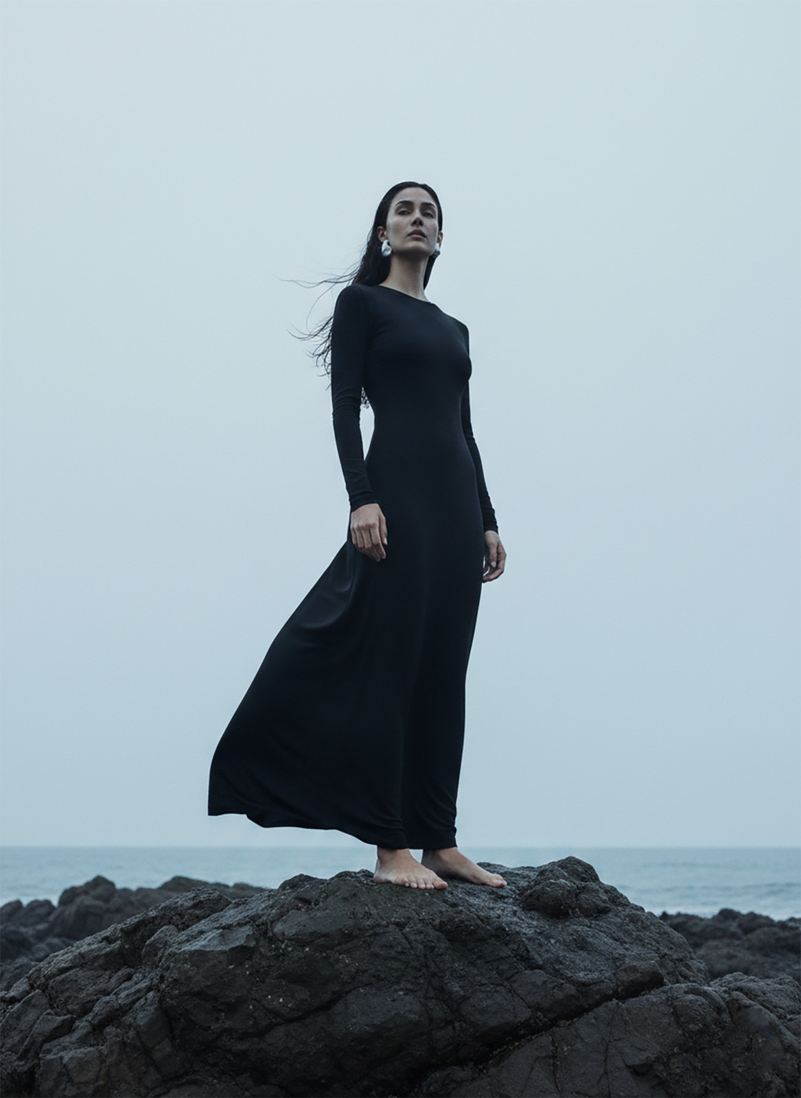 Figure in a black dress on volcanic rock wearing NEX Petroline earrings, CGI campaign by Sogand Nobahar