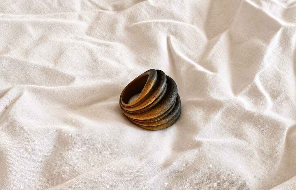 The ring on rumpled cream linen in soft side light, the visible weave and folds giving the eye a ruler for its size